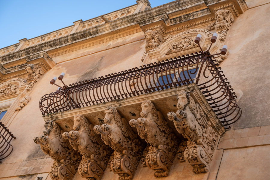 Sculpture de chevaux sous un balcon à Noto